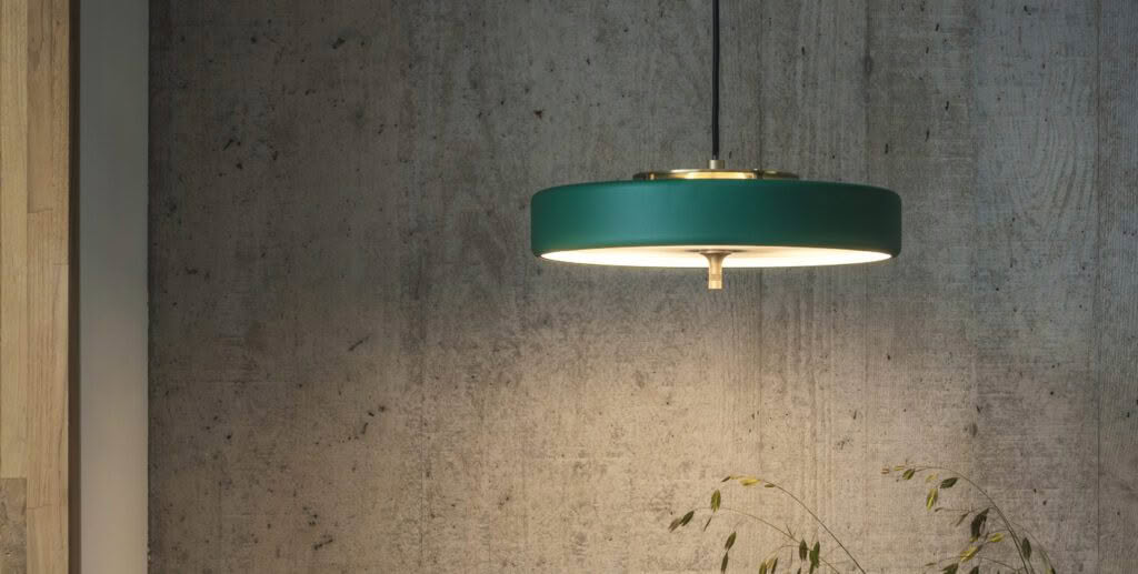 Green pendant light hanging against a concrete wall