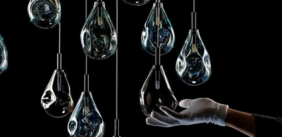 Gloved hand arranging suspended tear-shaped glass lamps
