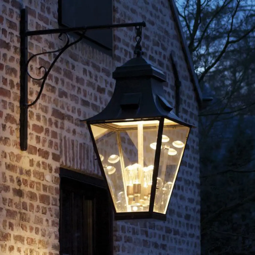 Illuminated lantern on brick wall at dusk