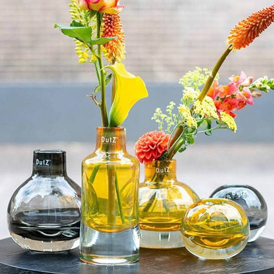Colorful flowers in Dutz branded glass vases on table