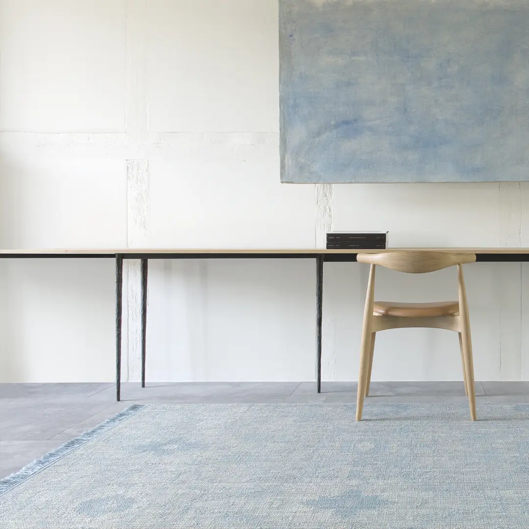 Minimalist office with abstract blue painting and wooden chair