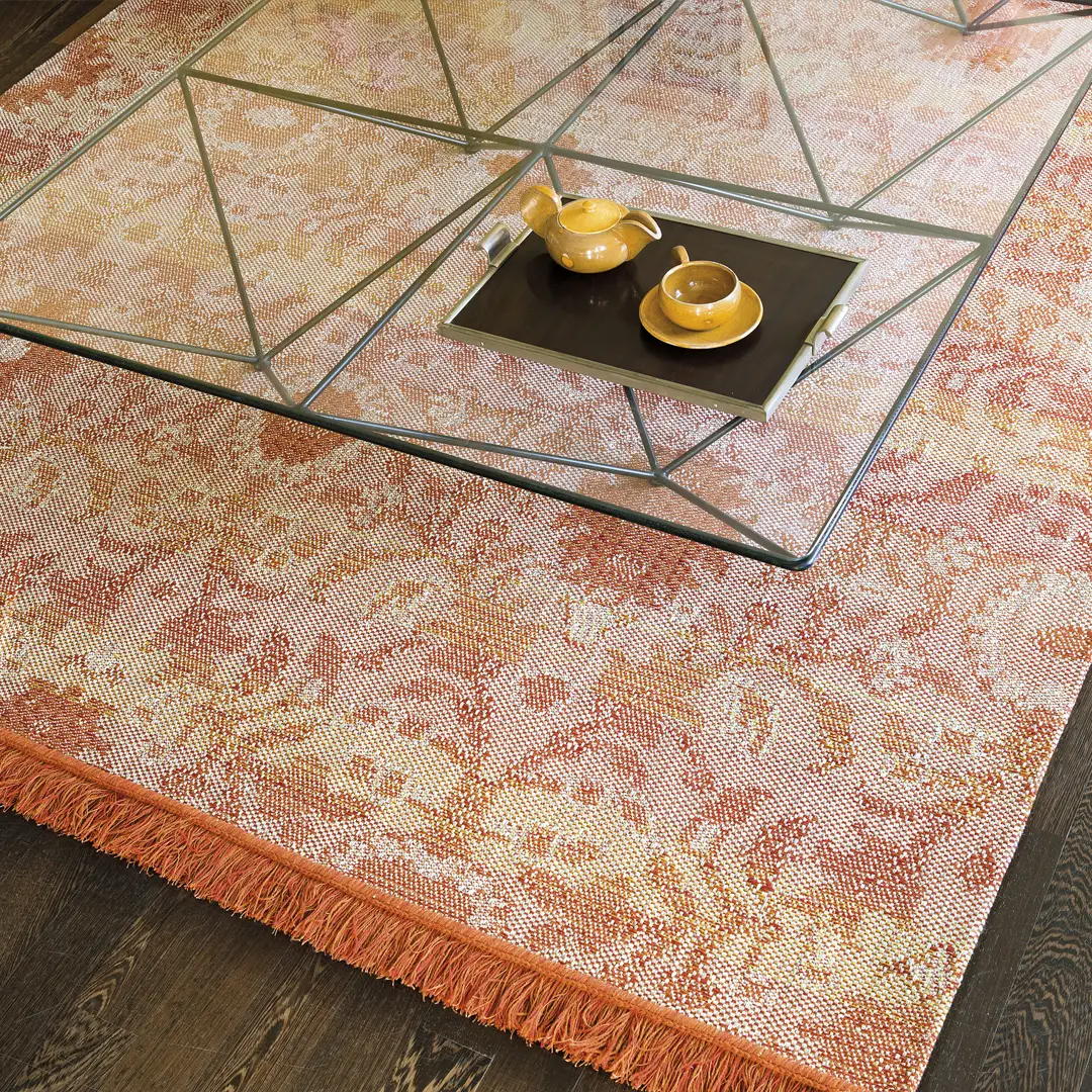 Glass coffee table on ornate orange carpet with teapot set