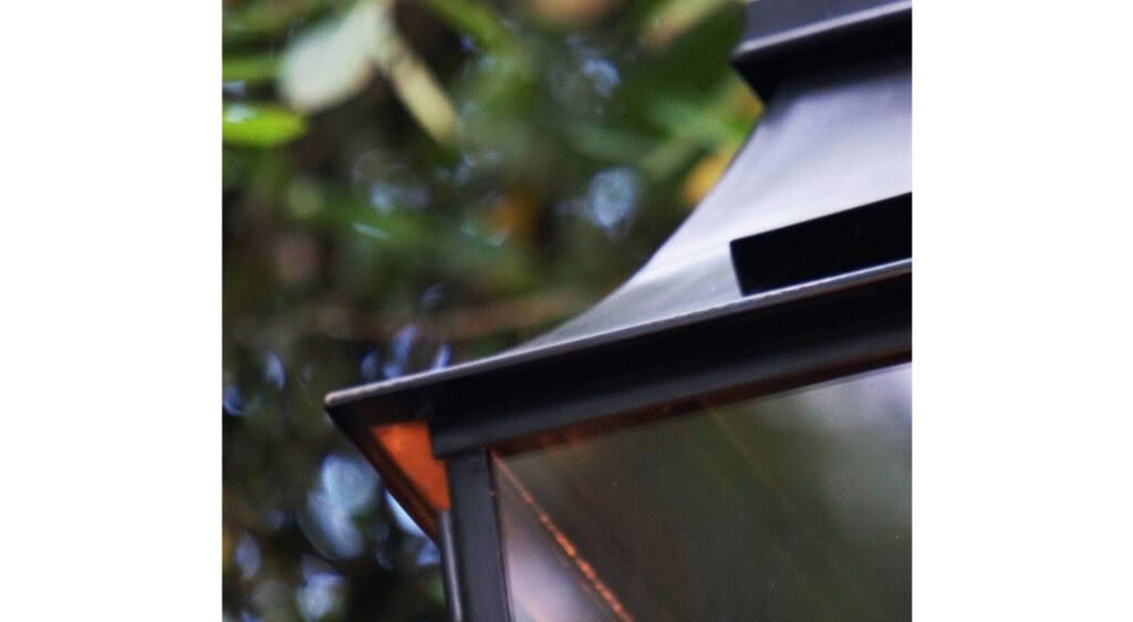 Close-up of modern outdoor lamp against green foliage