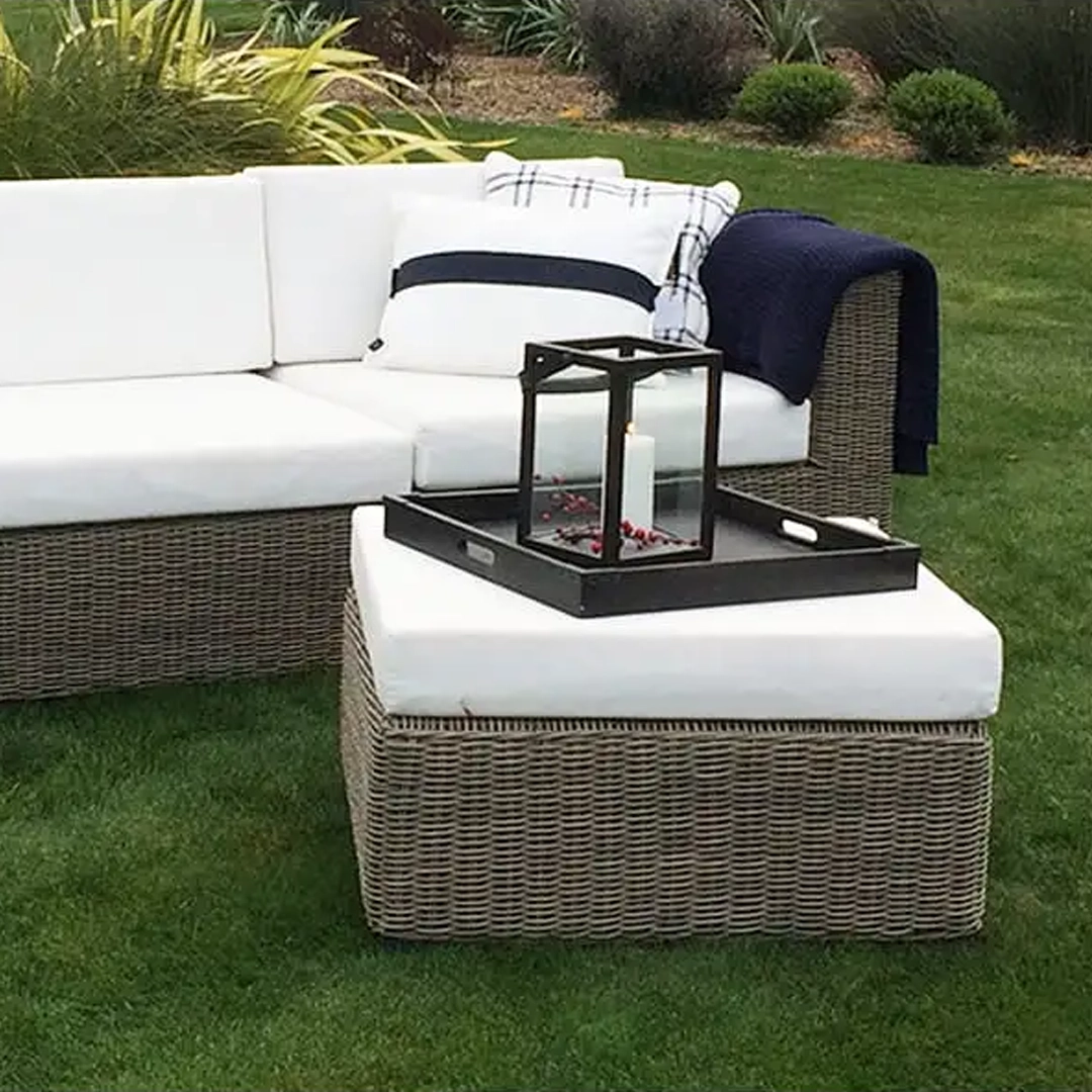 Outdoor wicker sofa with white cushions and lantern
