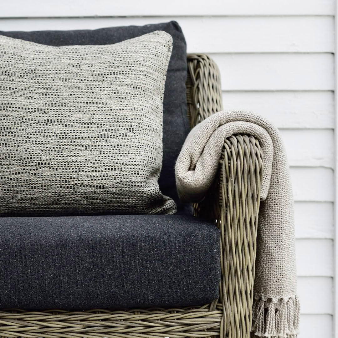 Cozy wicker chair with cushions and throw blanket