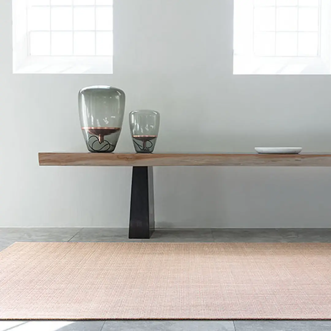 Minimalist wooden bench with glass vases and a rug