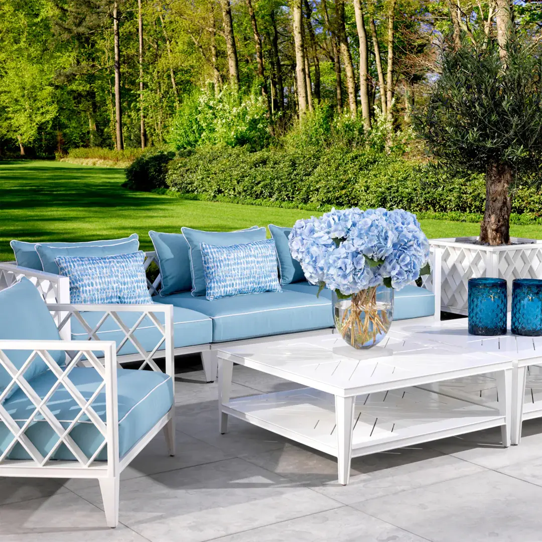 Outdoor patio furniture with blue cushions and forest backdrop