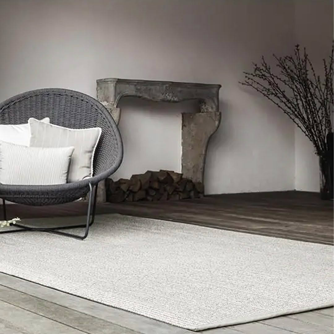 Modern wicker chair by rustic fireplace with wood pile.