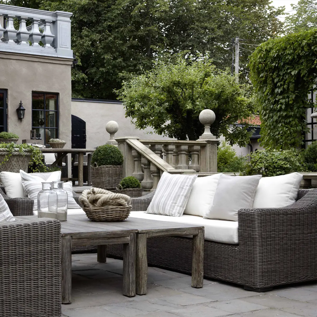Elegant outdoor patio with wicker furniture and greenery