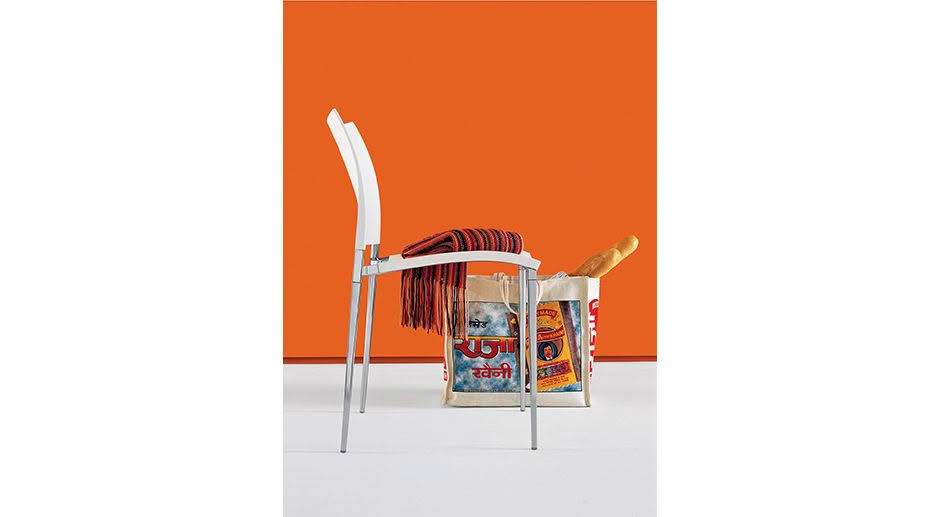 Chair, bread, and vibrant scarf against orange backdrop