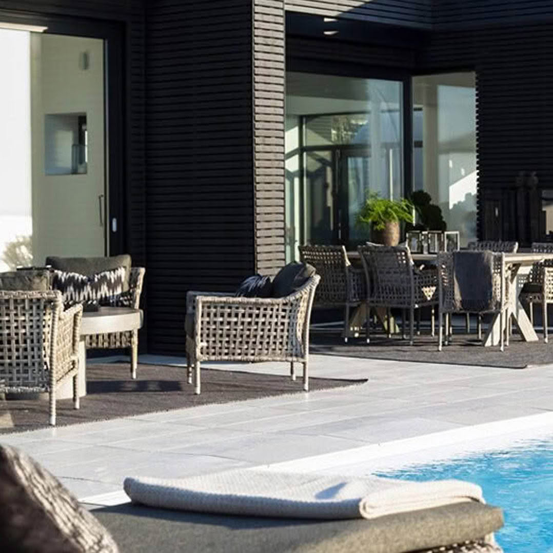 Modern poolside patio with stylish furniture and house