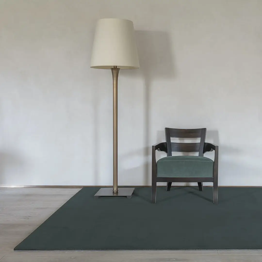 Modern lamp and chair on green rug in room