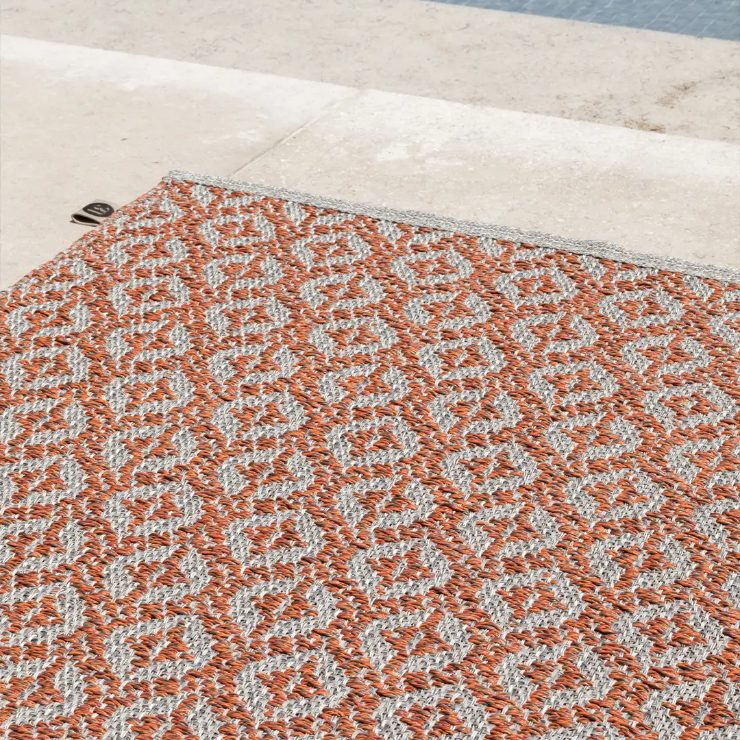 Orange and gray patterned rug on concrete surface