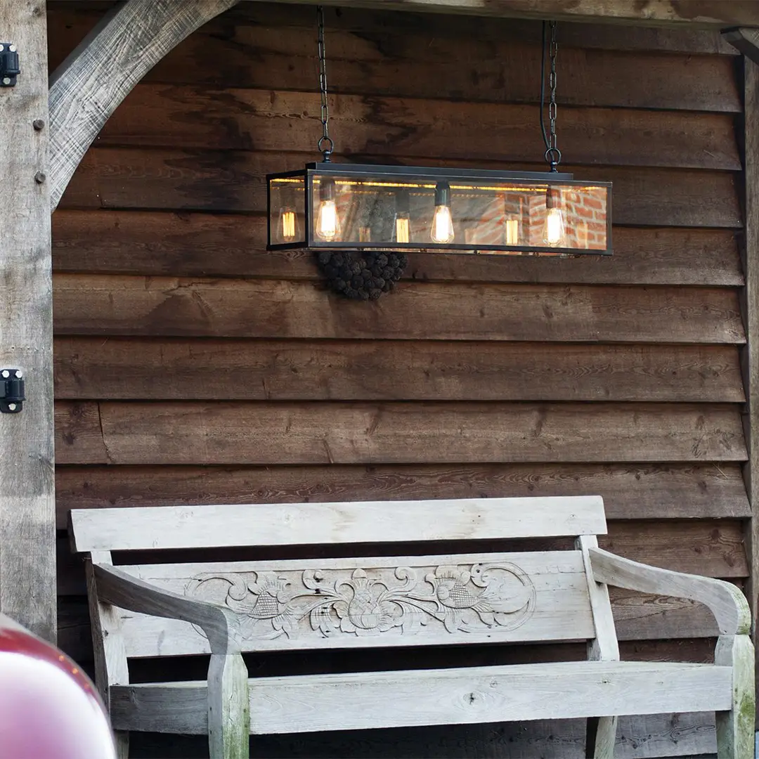 Rustic wooden bench under hanging light in cabin.