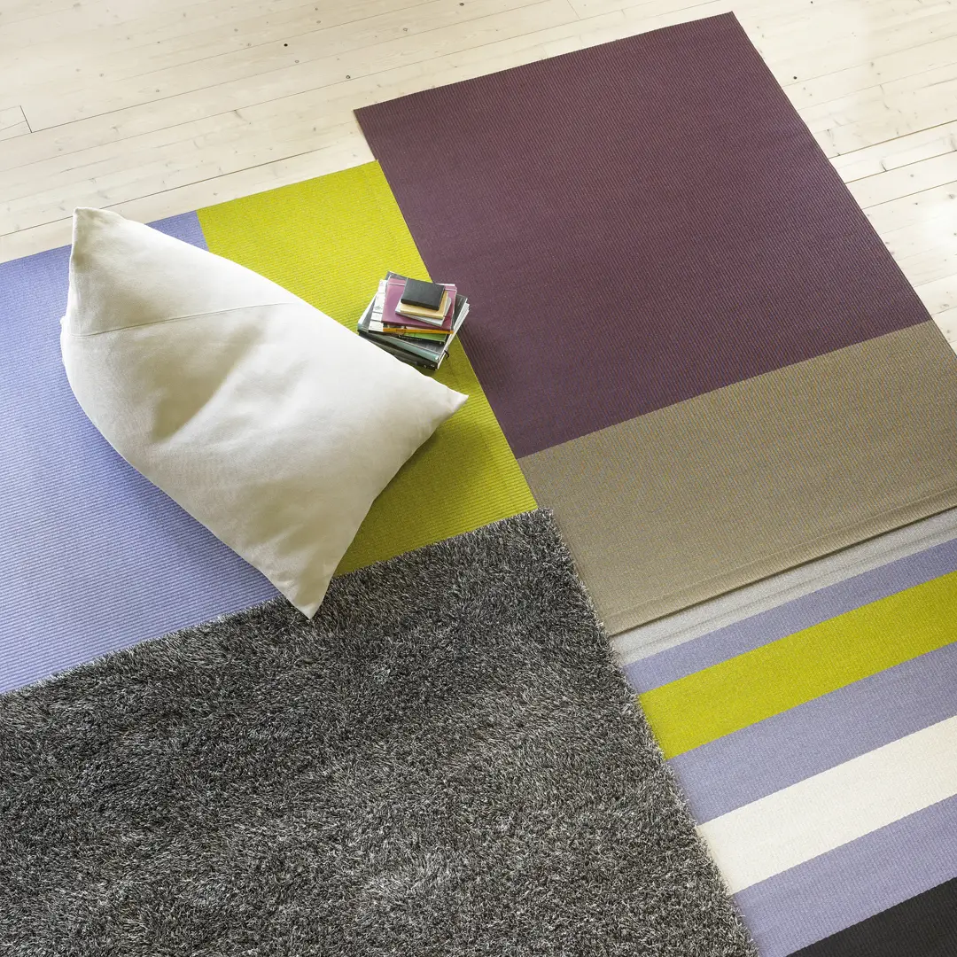 Colorful area rugs with pillow and books top view