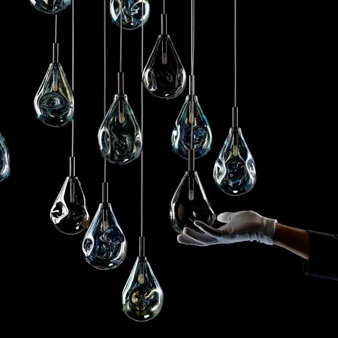 Hand touching one of several hanging glass orbs