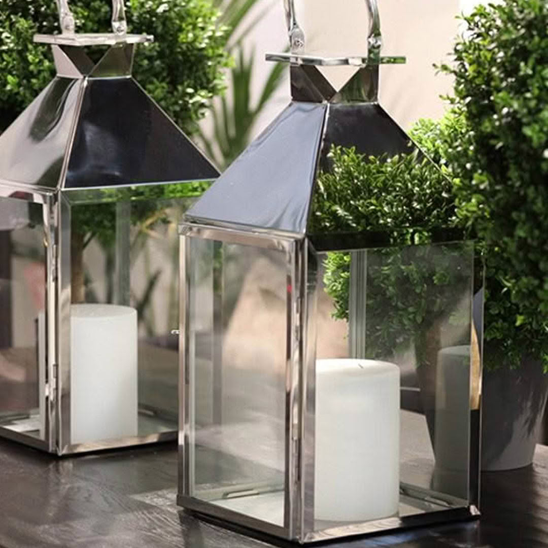 Modern glass lanterns with white candles on wooden table