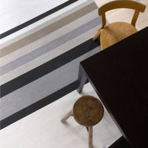 Striped rug, wooden chair and dark table in room