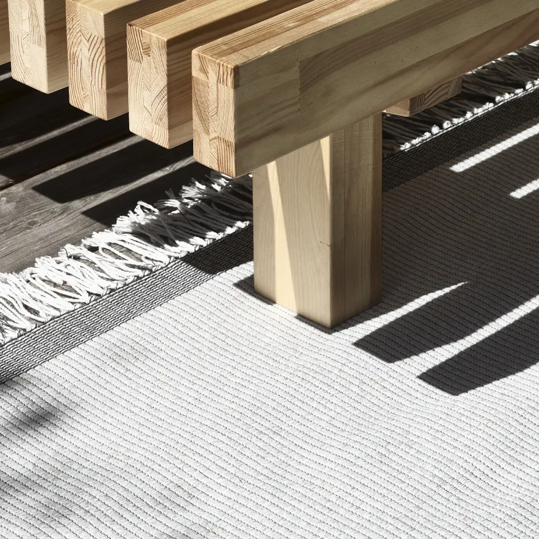 Wooden bench legs on striped rug with shadows