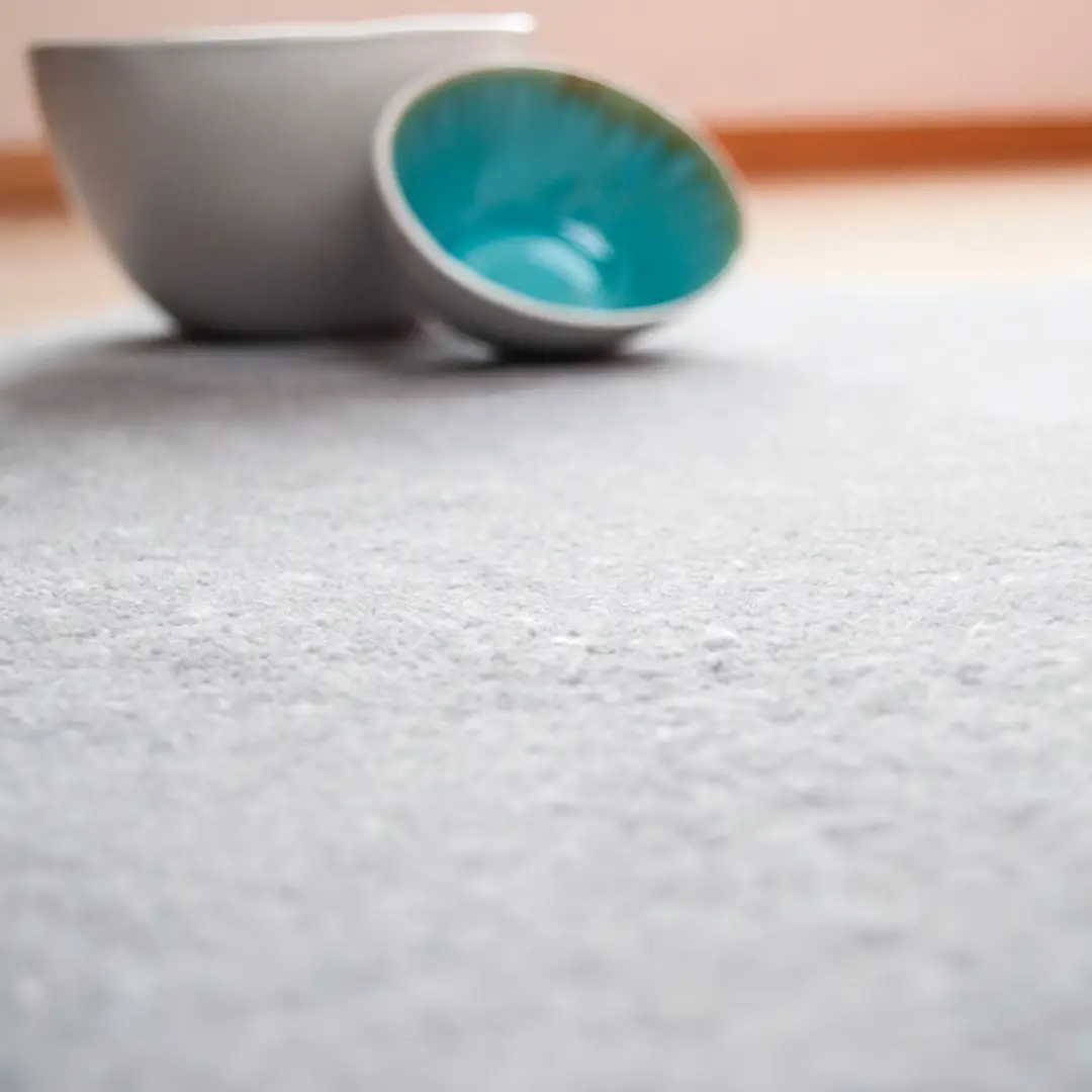 Two ceramic bowls on textured carpet, focus on turquoise
