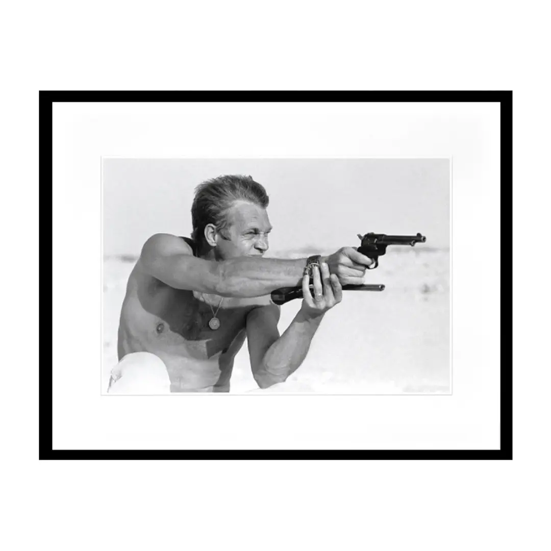 Man aiming two guns on beach in black and white