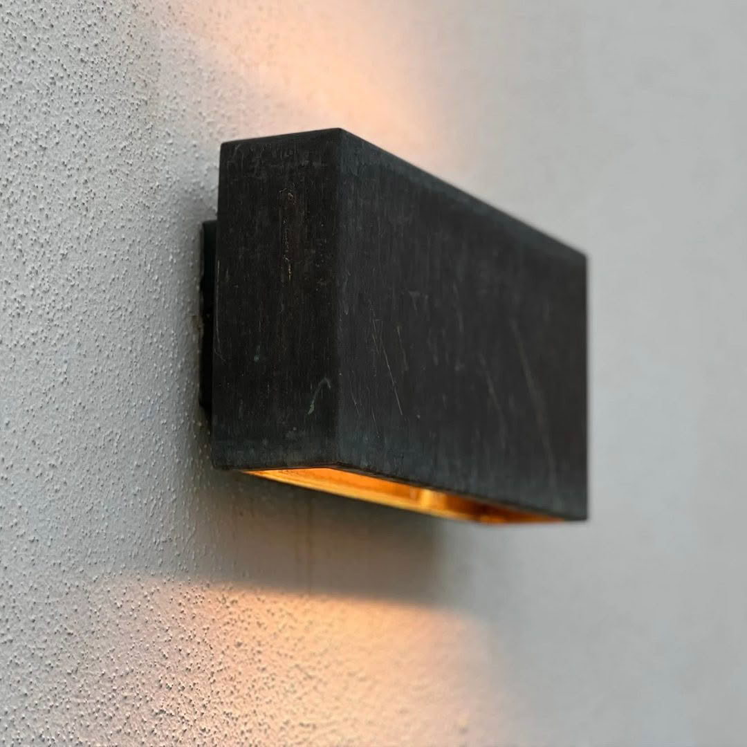 Modern black wall lamp with soft glow on gray surface