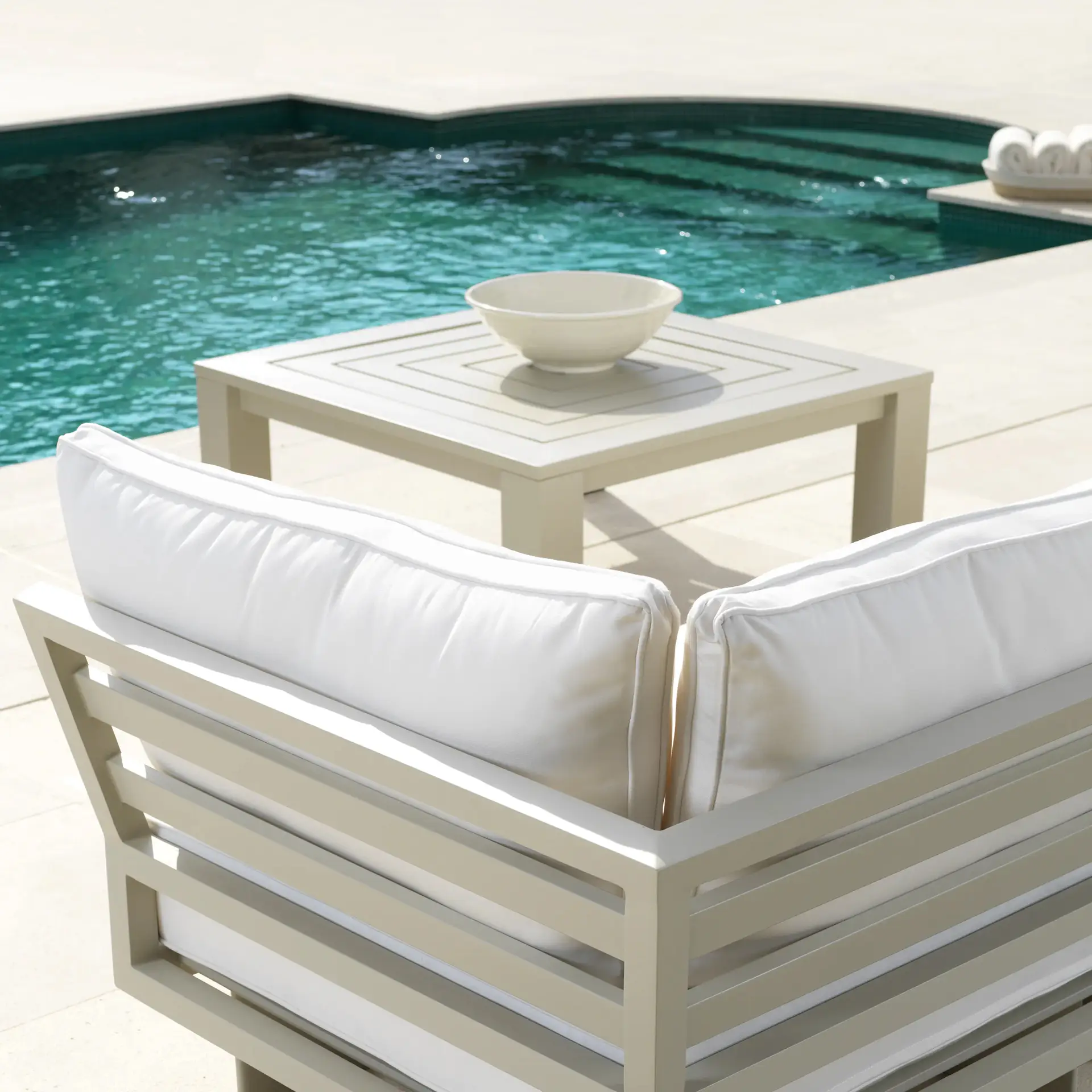 Outdoor poolside furniture with white cushions and table