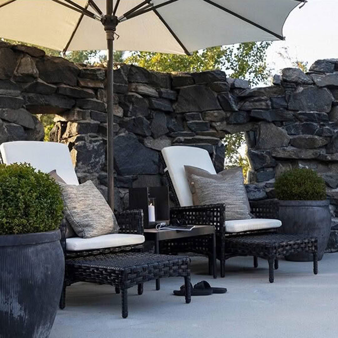 Stylish outdoor patio seating with umbrella and stone wall