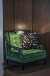 Green velvet chair with decorative pillow and reading lamp