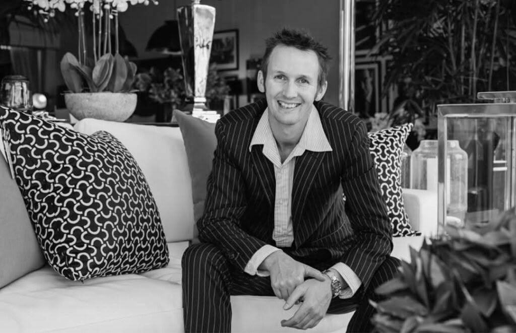 Smiling man in pinstripe suit seated on white sofa