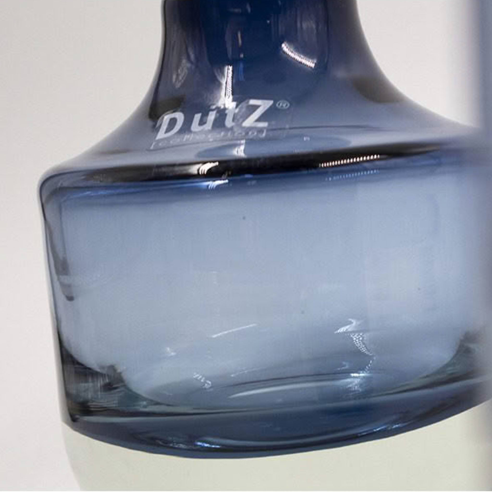 Close-up of blue DutZ glass vase against white background