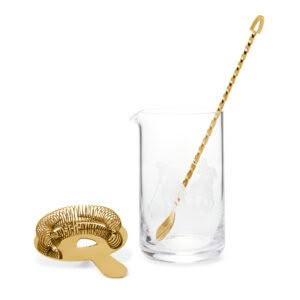 Gold stirring rod in glass cup next to coil whisk