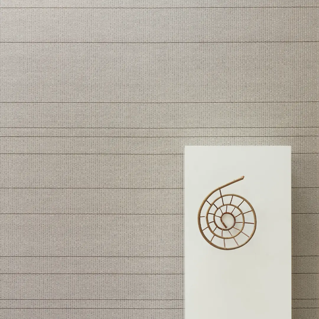 Spiral sculpture on white pedestal against striped wall