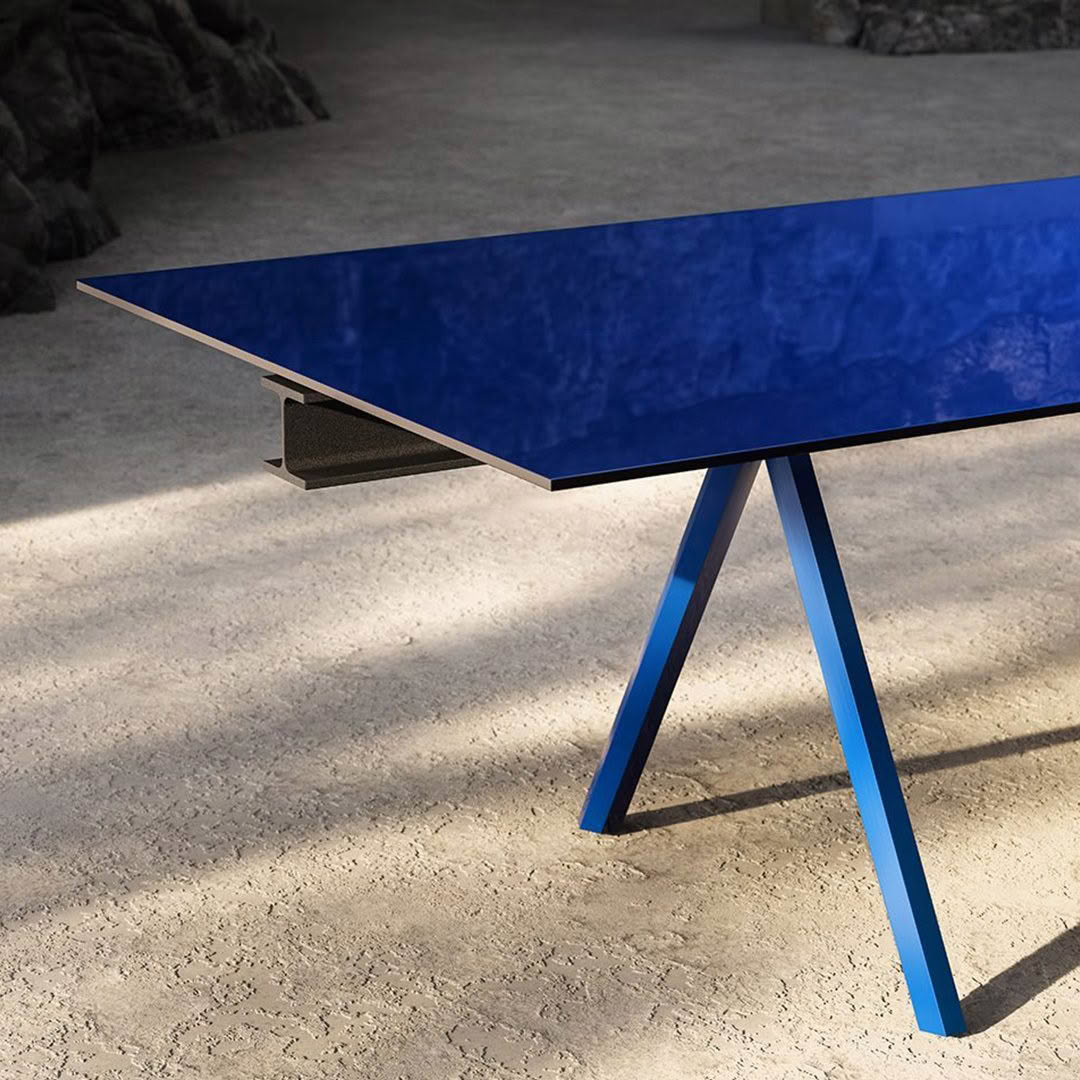 Blue triangular modern table on sandy floor
