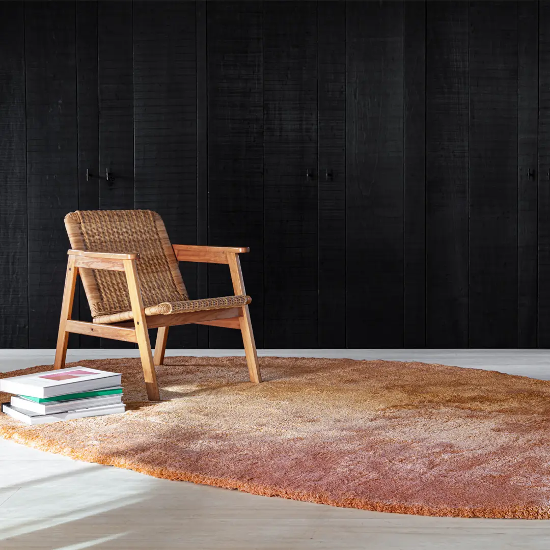 Wooden chair on textured rug against black wall