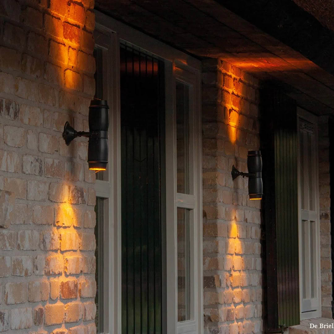 Illuminated lanterns on brick wall at twilight