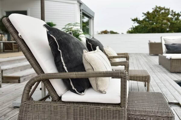 Outdoor rattan lounge chair with cushions on deck