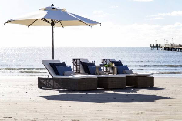 Beach lounge chairs under umbrella near ocean