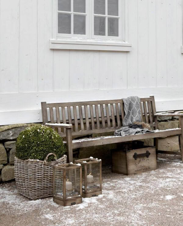 Snowy outdoor bench with cozy blanket and lanterns