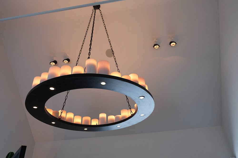 Modern circular chandelier with lit candles hanging indoors