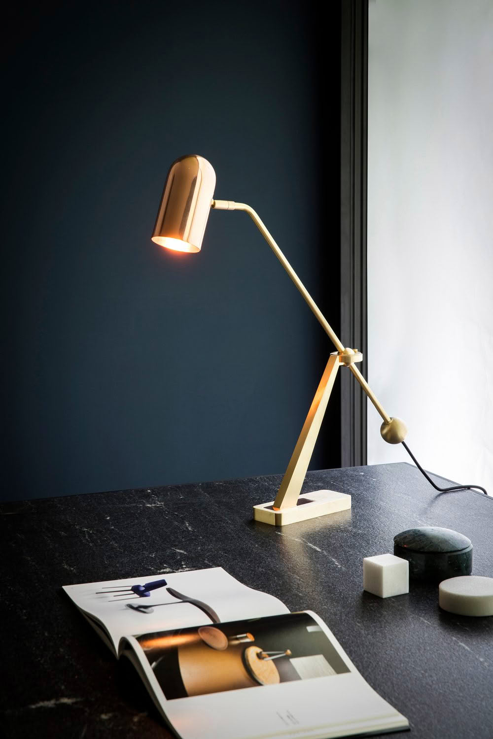 Modern desk lamp illuminating a magazine on dark table