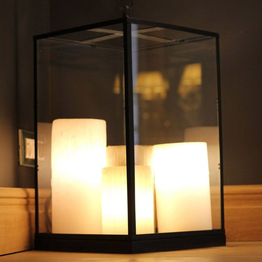 Illuminated candles inside a modern glass lantern