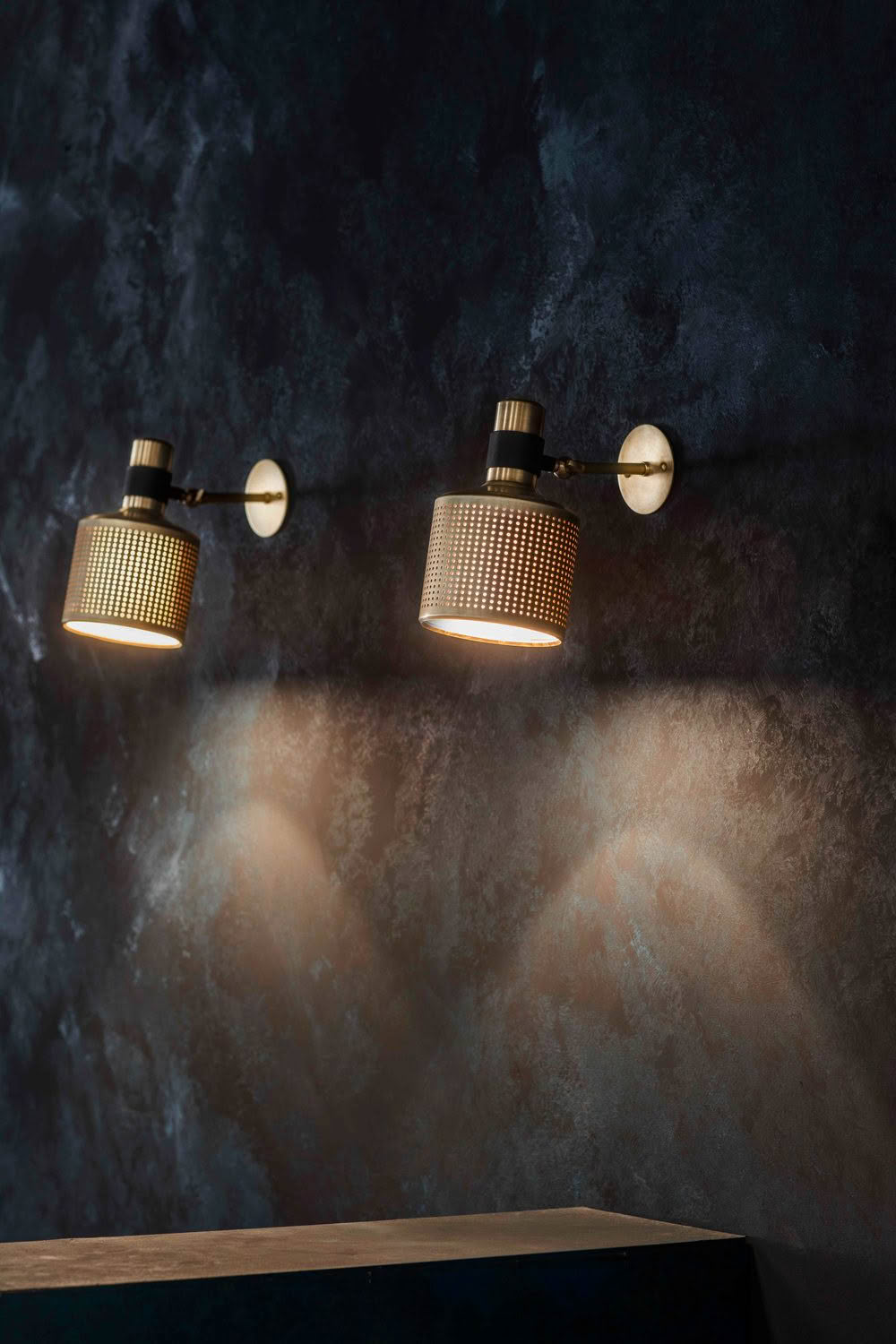 Three modern wall lights illuminating textured dark wall