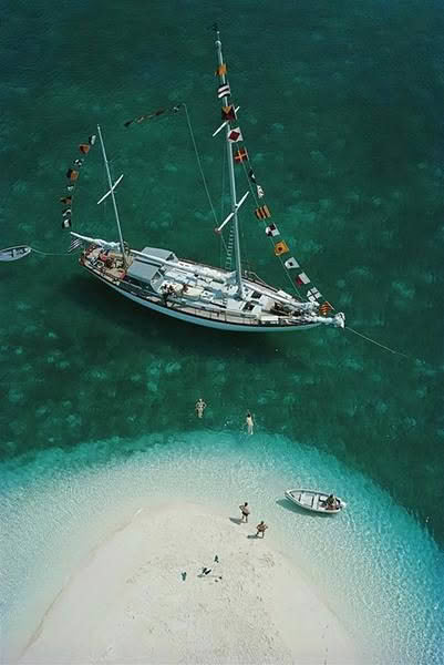 Yacht anchored near small sandy island with swimmers
