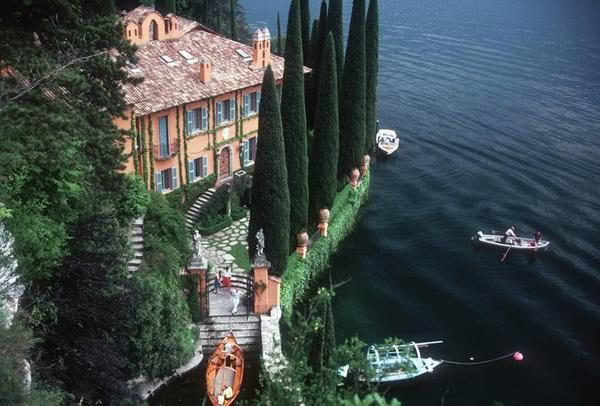 Scenic lakeside villa with boats and lush greenery