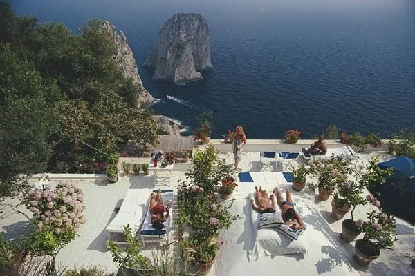 Cliffside resort terrace with people sunbathing by sea
