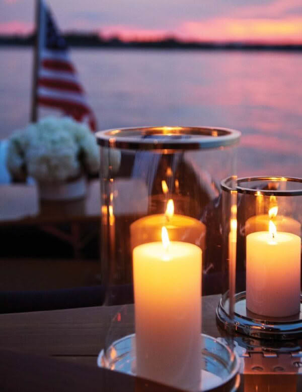Candles on table near water at sunset with American flag