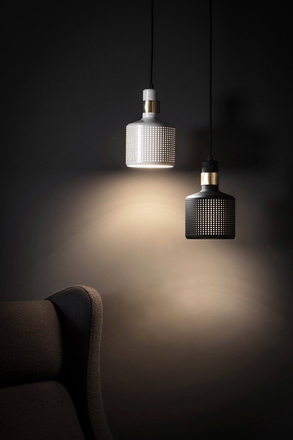 Modern pendant lights illuminating dark room with chair