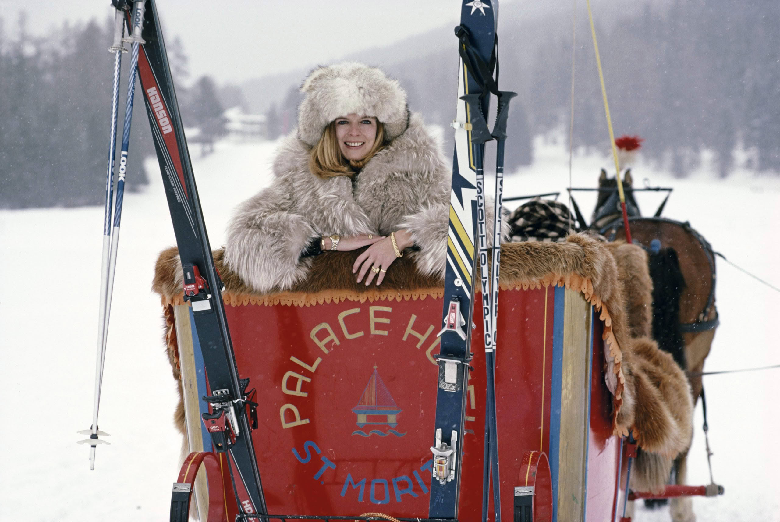 Woman in fur hat smiling on a horse-drawn sled