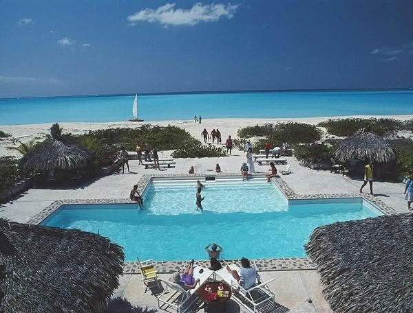 Tropical resort poolside with ocean view and beachgoers